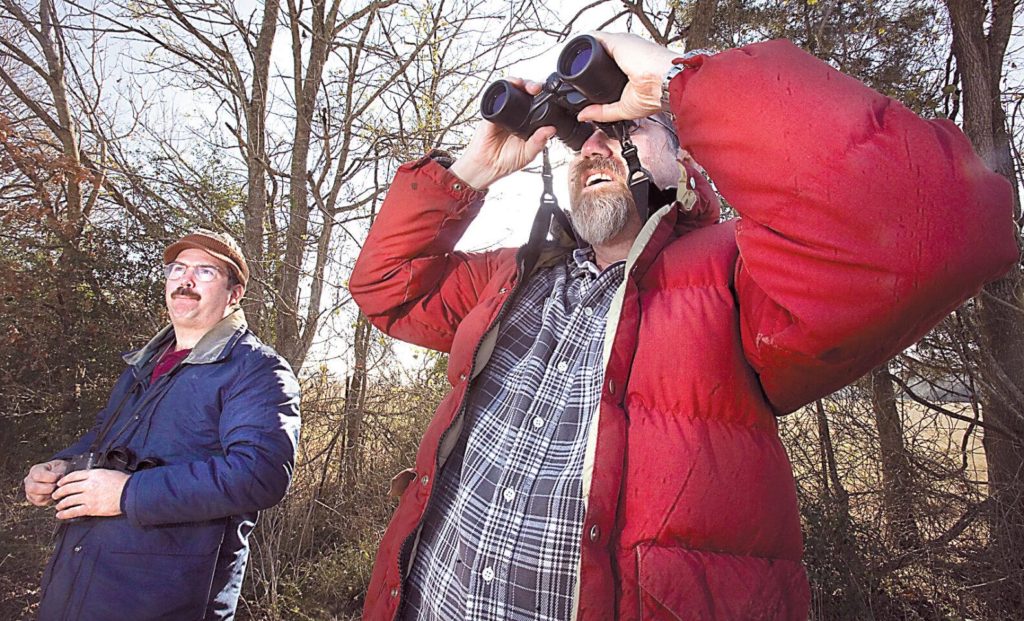 Two men with binoculars look for birds during a Christmas bird count.